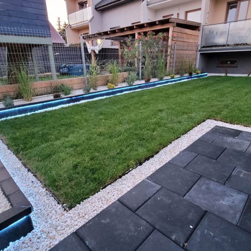Nowoczesny ogród z trawnikiem, płytami i obrzeżem z białych kamieni